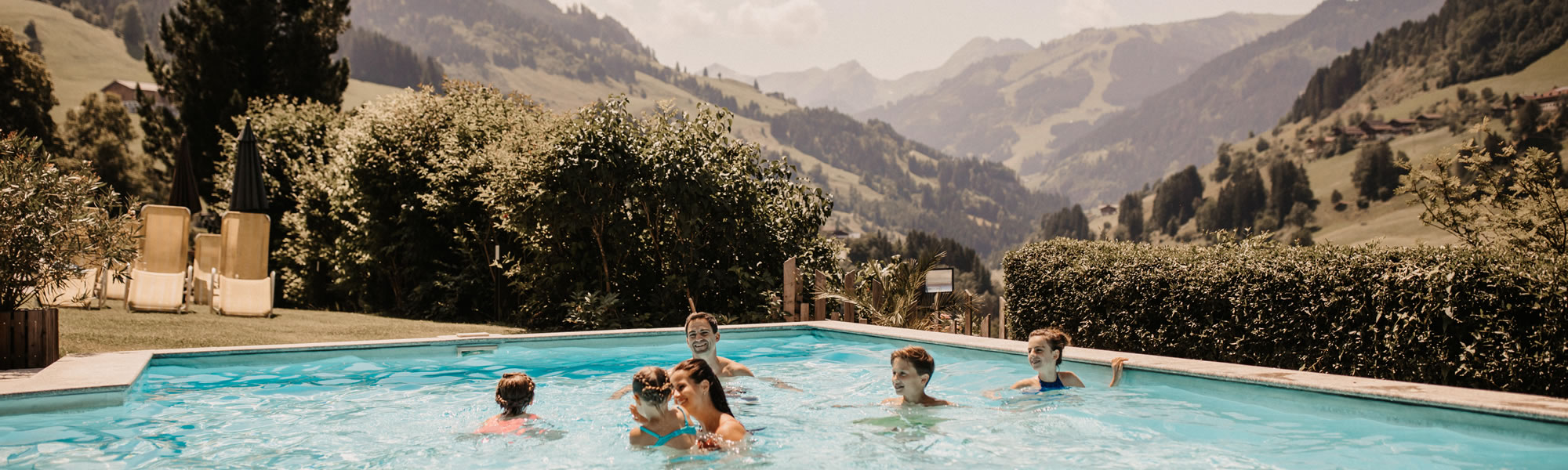 Familie im Pool mit Ausblick auf die Berge © Selina Flasch